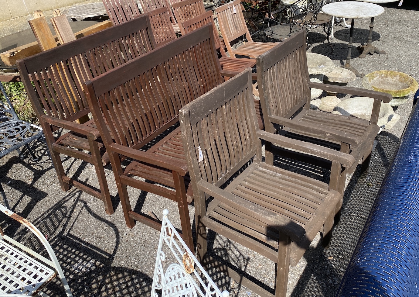 A pair of stained teak garden benches, width 121cm, height 99cm, and a pair of matching elbow chairs